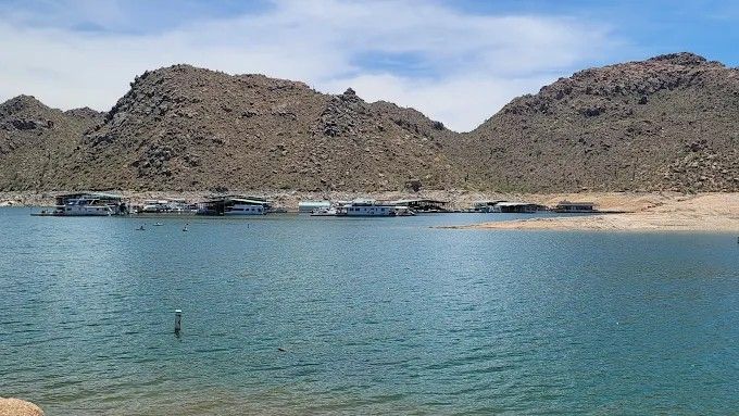 Blue lake with docked houseboats and rocky mountains in the background.