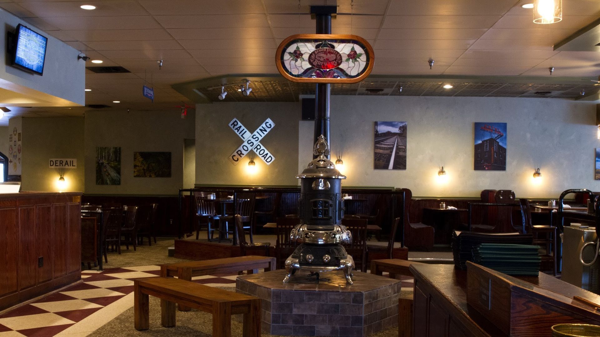 Interior of a restaurant with booths and tables. A decorative railroad crossing sign hangs on the wall.