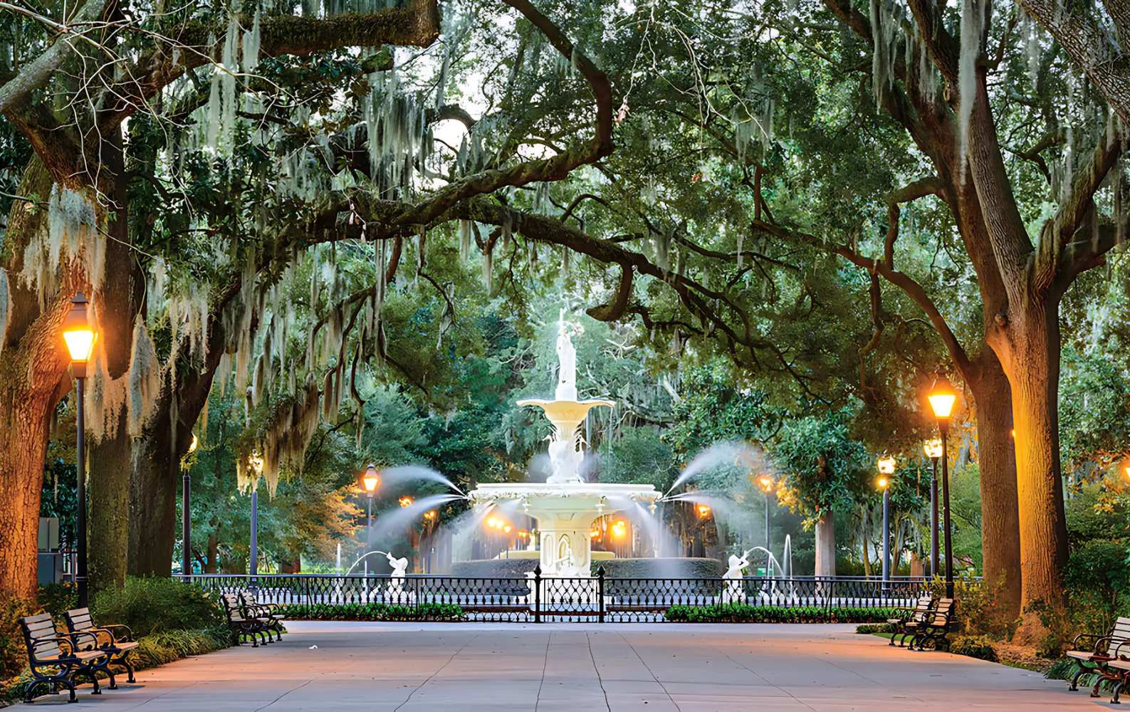 A fountain in a park surrounded by trees and benches in Savannah, GA