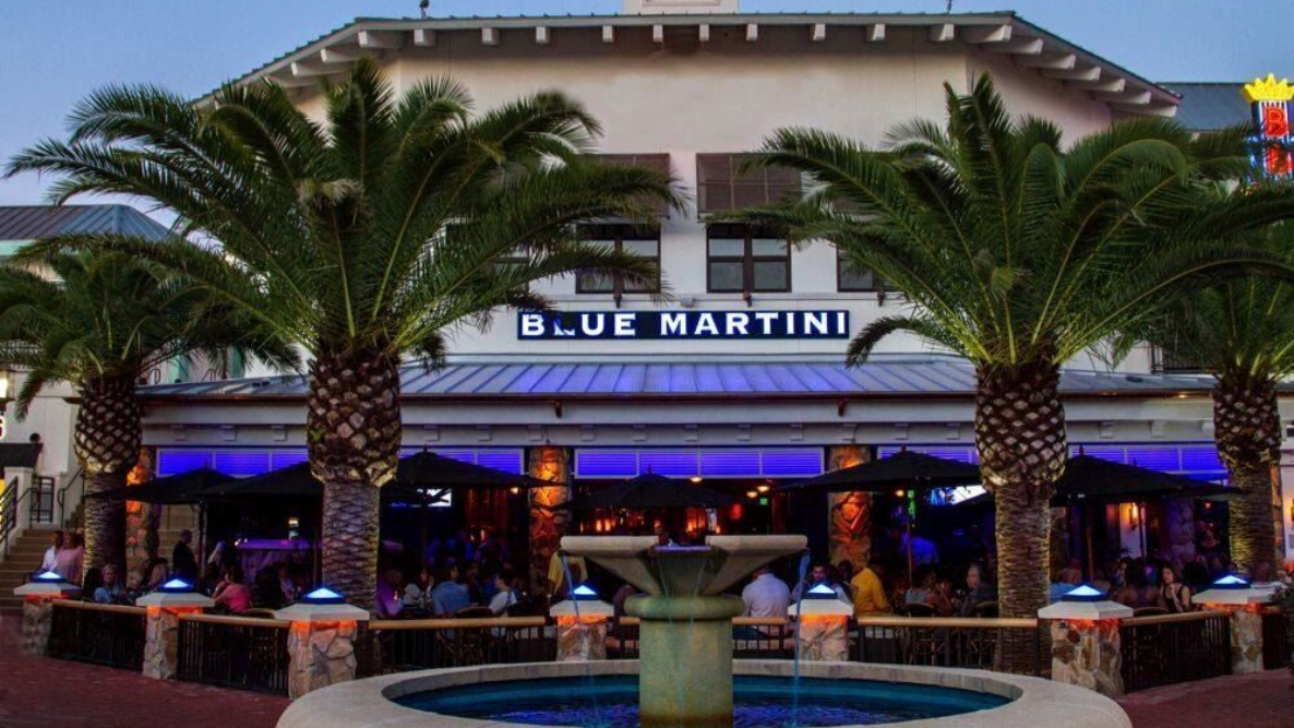Blue Martini restaurant exterior with palm trees, fountain, and illuminated bar area.