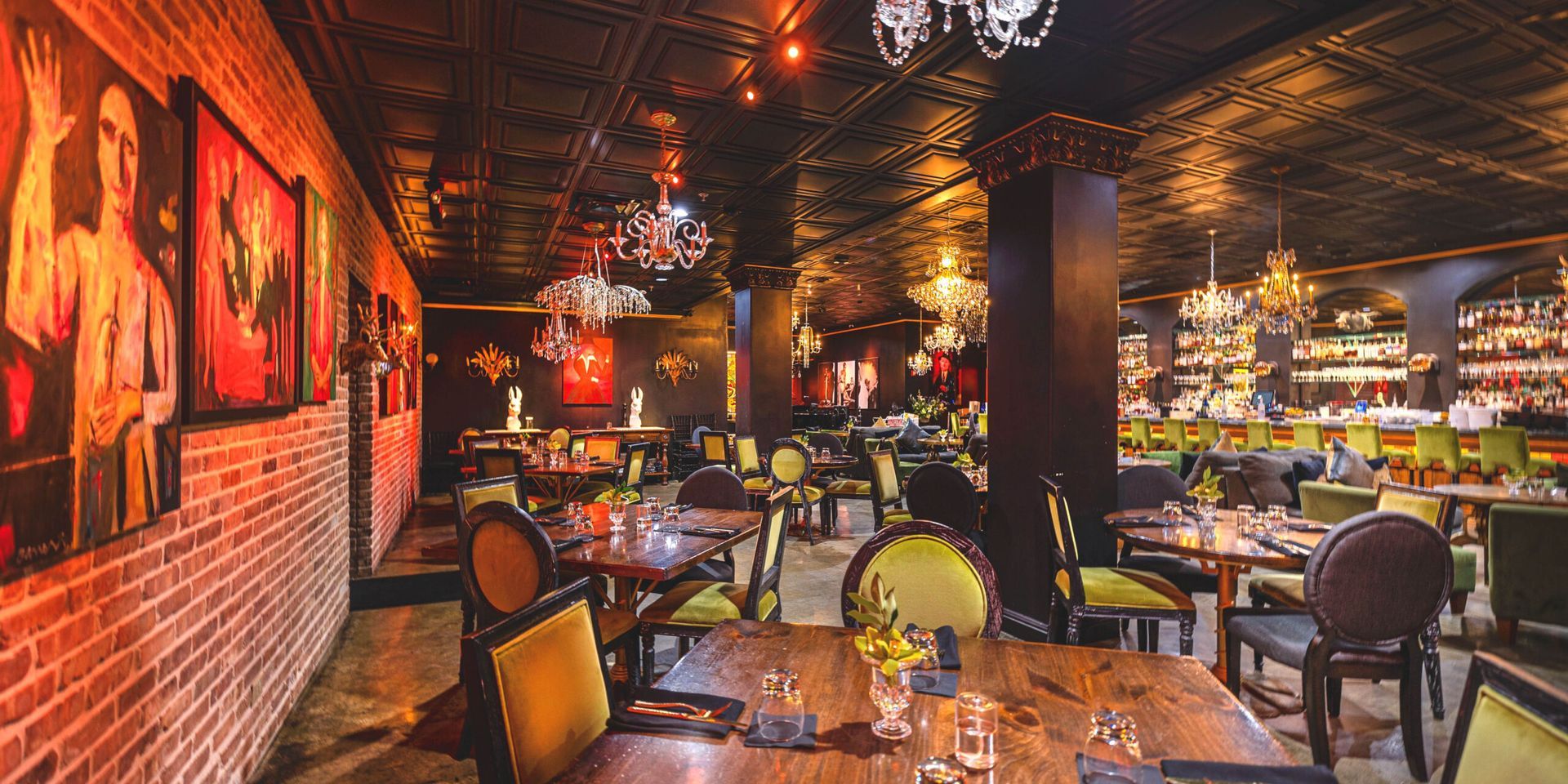 Restaurant interior with exposed brick, chandeliers, and tables set for dining.