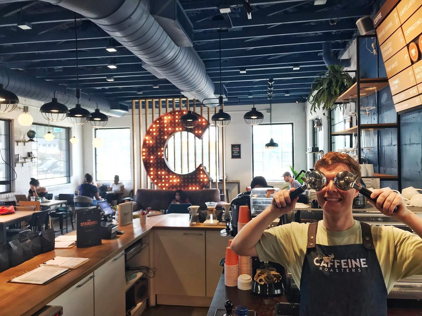 Barista holding coffee tools in front of his eyes in a coffee shop with the letter