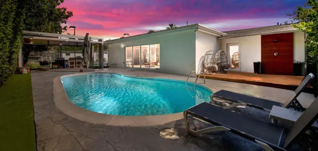 A large swimming pool is in the backyard of a house.
