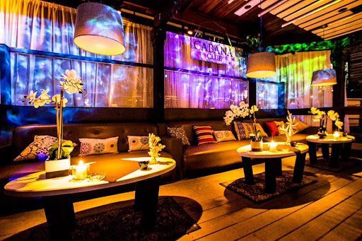 Dimly lit lounge with couches, round tables, candles, and projected lights on walls.