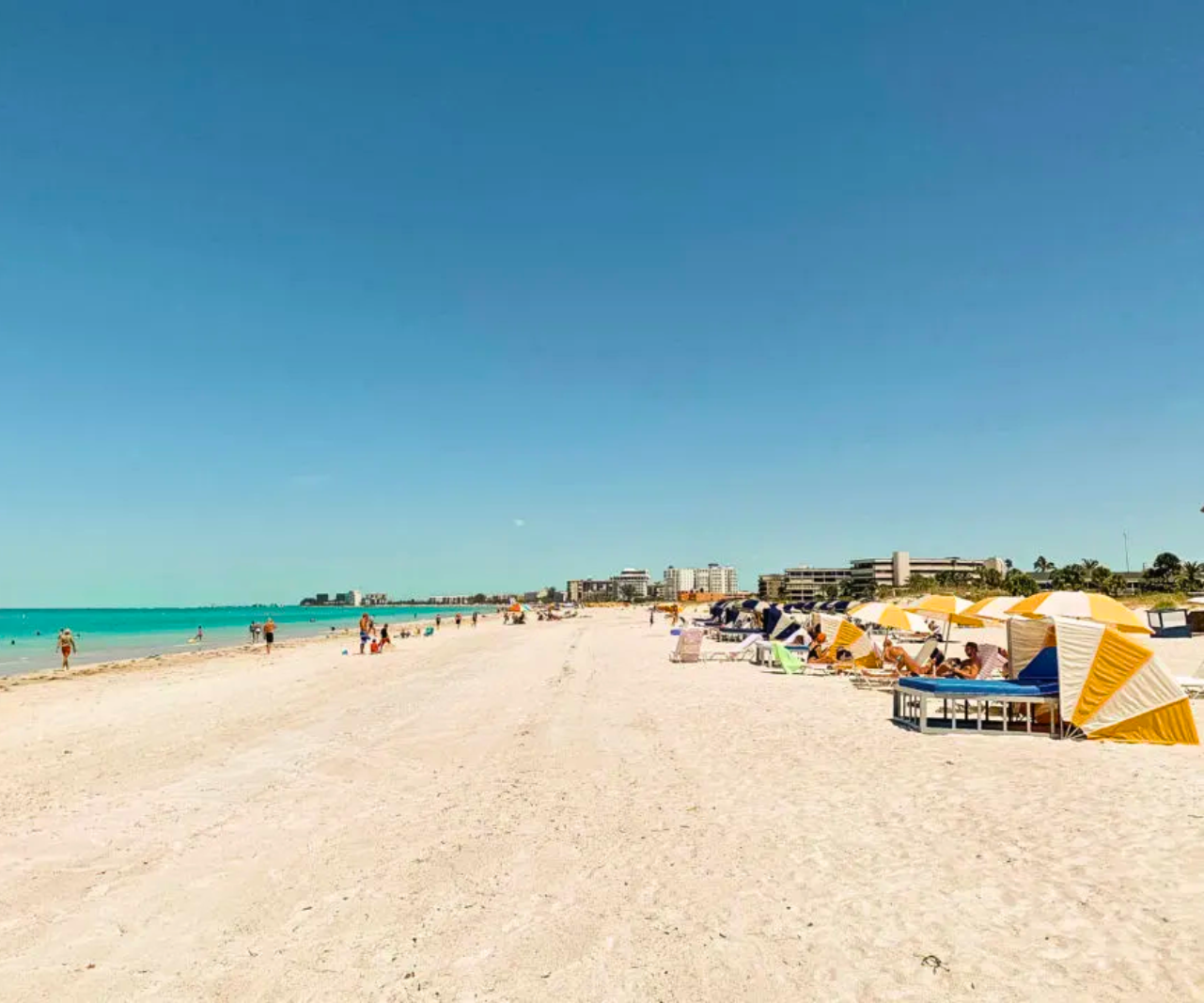 A beach with umbrellas and chairs on a sunny day.