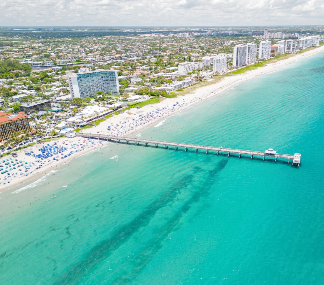 An aerial view of a Clearwater Beach, with the pier jutting out into the ocean.