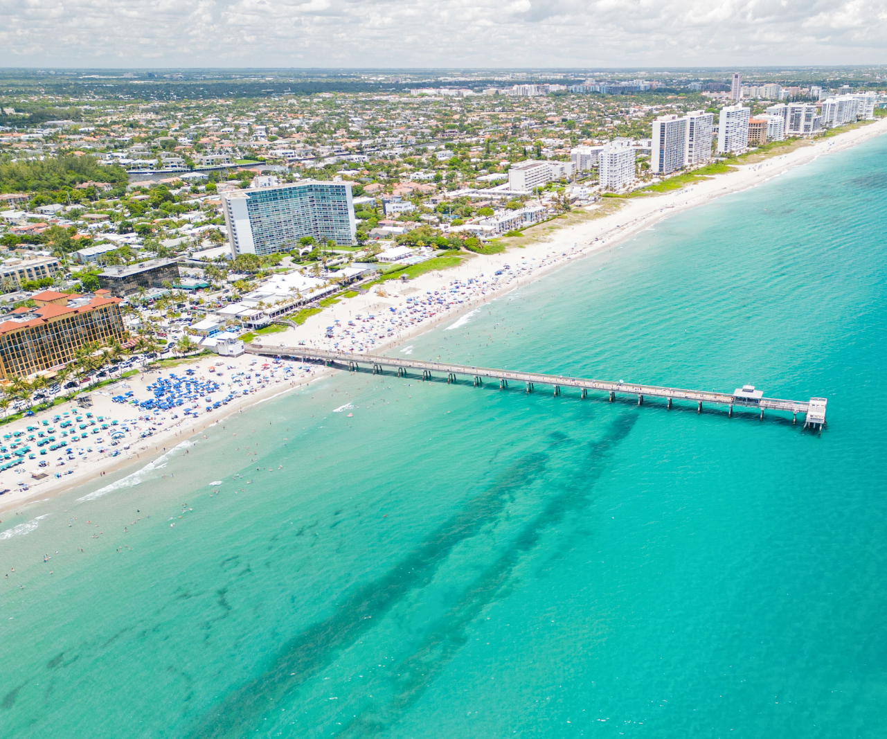 An aerial view of a Clearwater Beach, with the pier jutting out into the ocean.