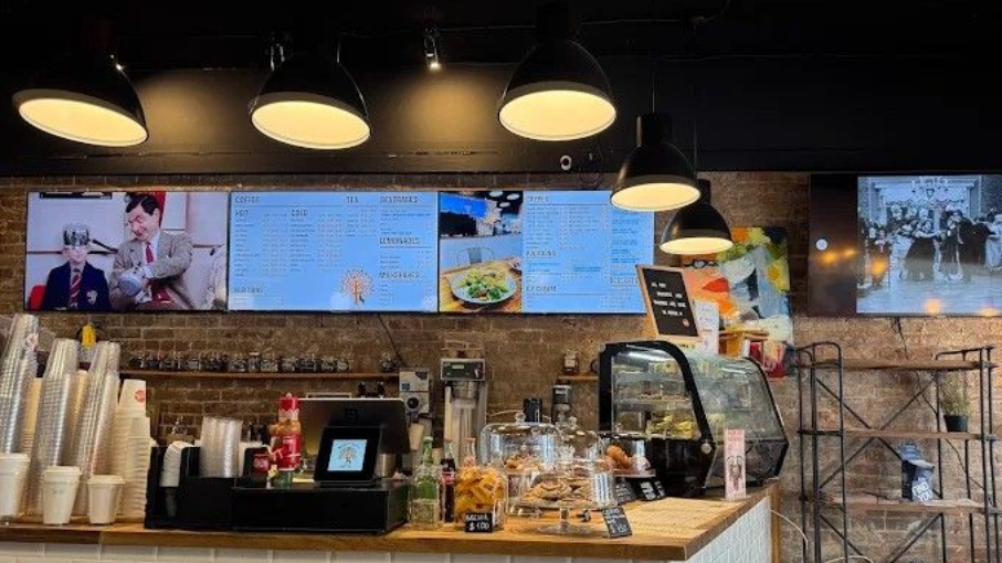 Coffee shop counter with menu screens, lamps, and pastries.