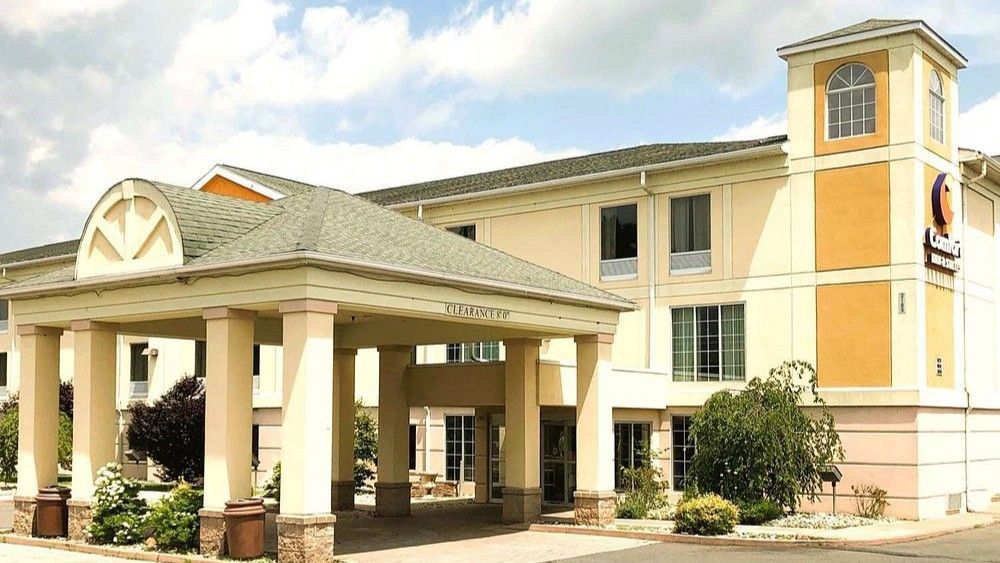Hotel exterior with tan walls, columns, and a covered entrance.