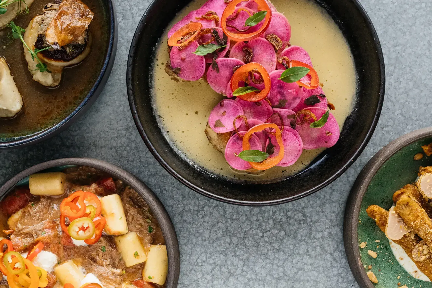Bowls of various dishes, including one with pickled beets and another with stew.