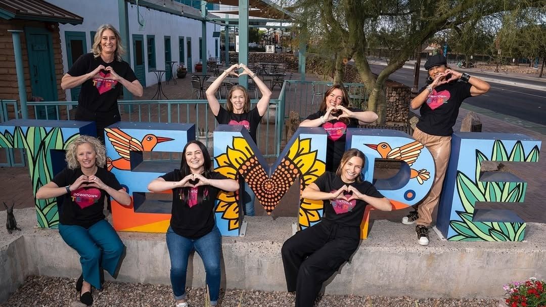 Group of people forming hearts, smiling, and posing in front of 