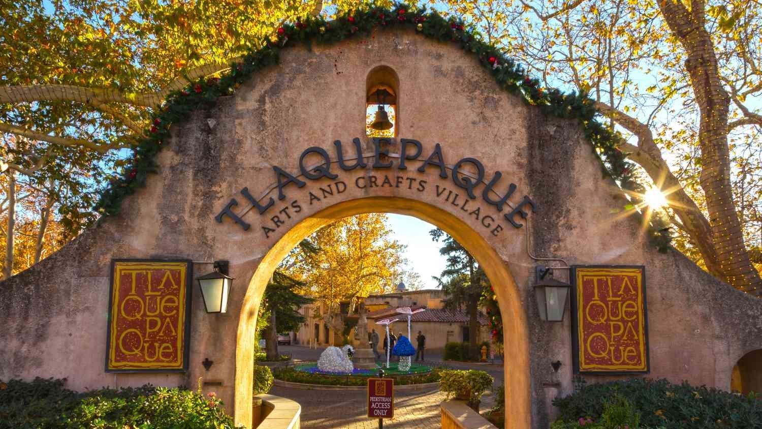 Tlaquepaque Arts and Crafts Village archway in Sedona, Arizona. Stone facade, bell, and fall foliage.