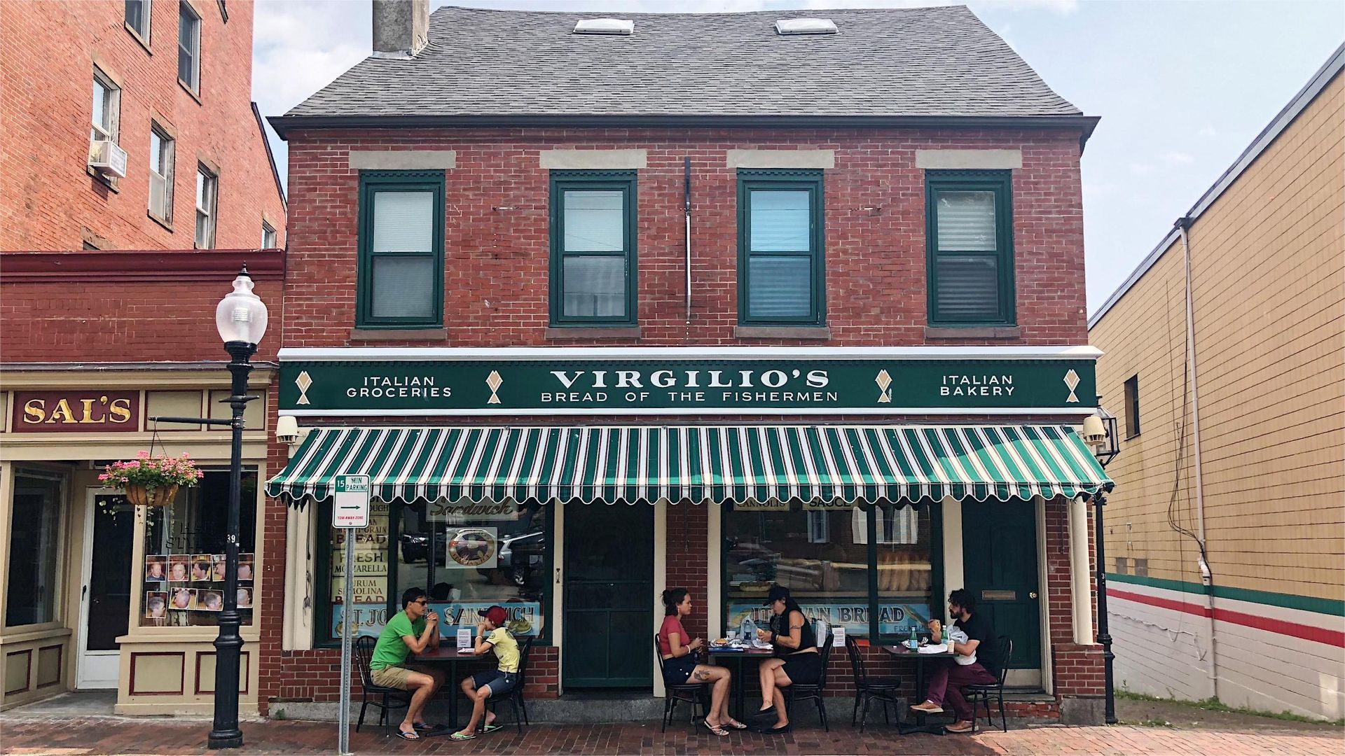 Virgilio's Italian restaurant with green awning, brick facade, and outdoor seating. People are seated at tables.