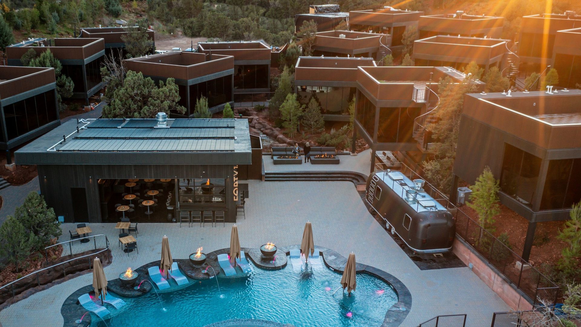 Resort with geometric buildings, pool, and vintage train car in outdoor setting.