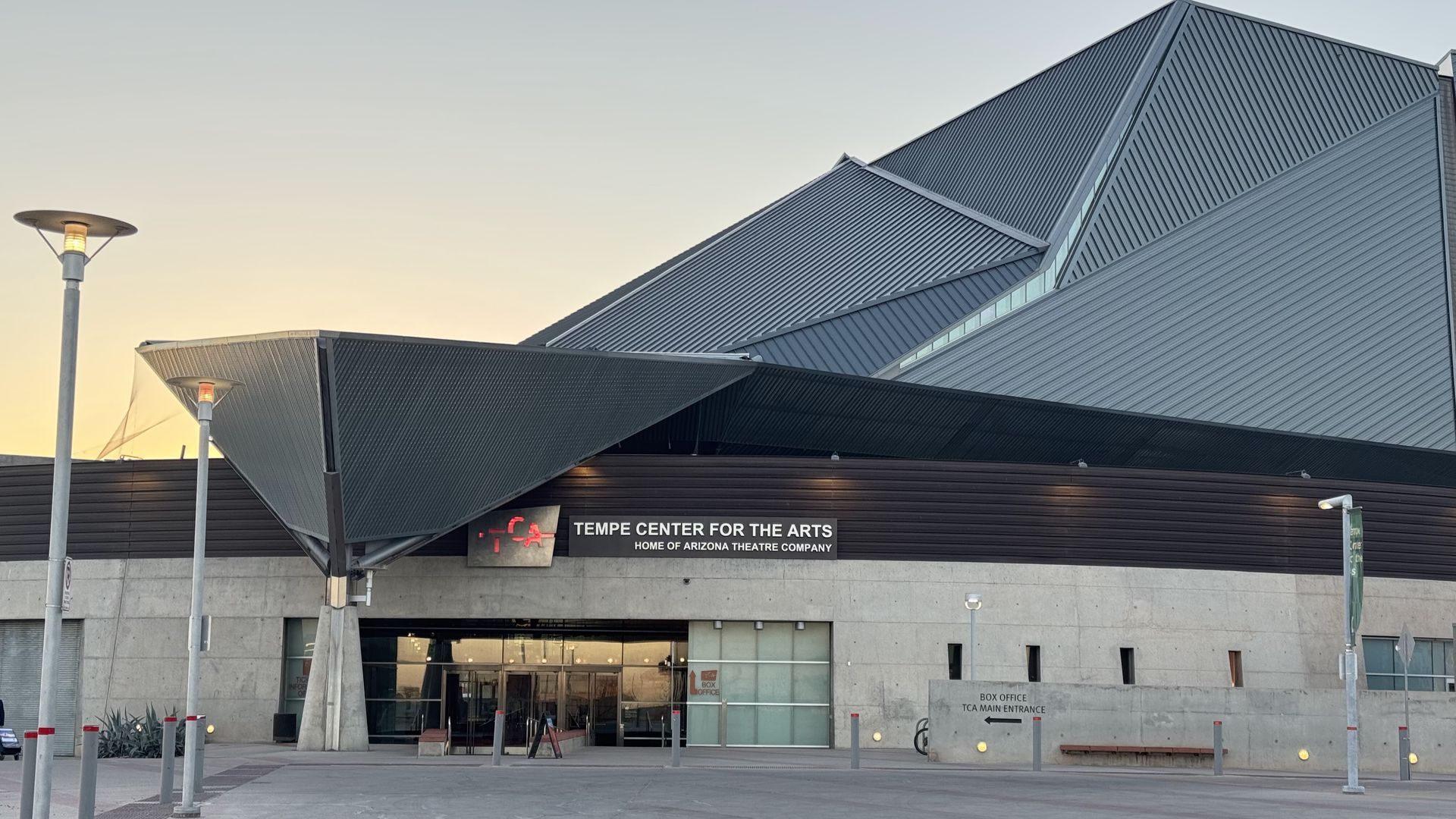 Modern building with angular, dark roof and a sign reading