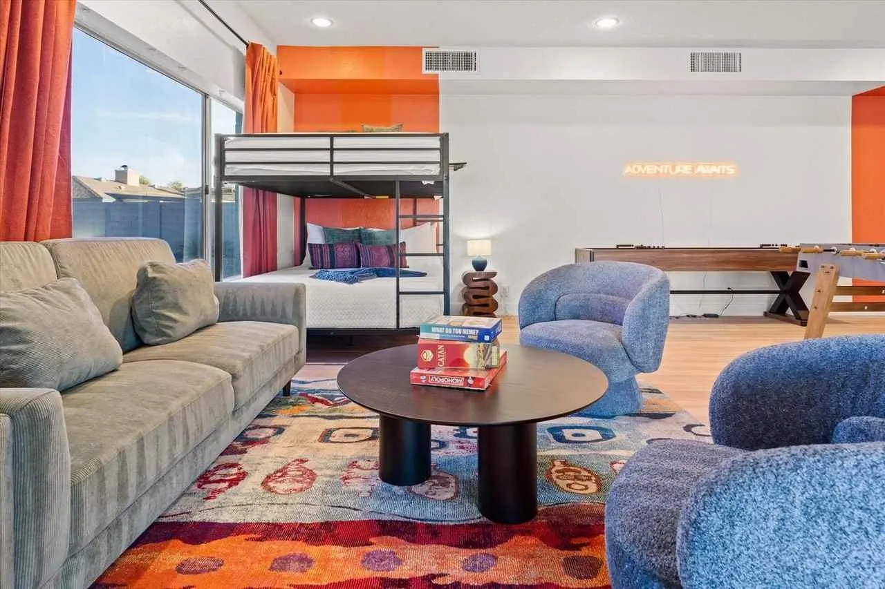 Modern lounge with sofas, round coffee table, bunk bed, and colorful rug in a bright room