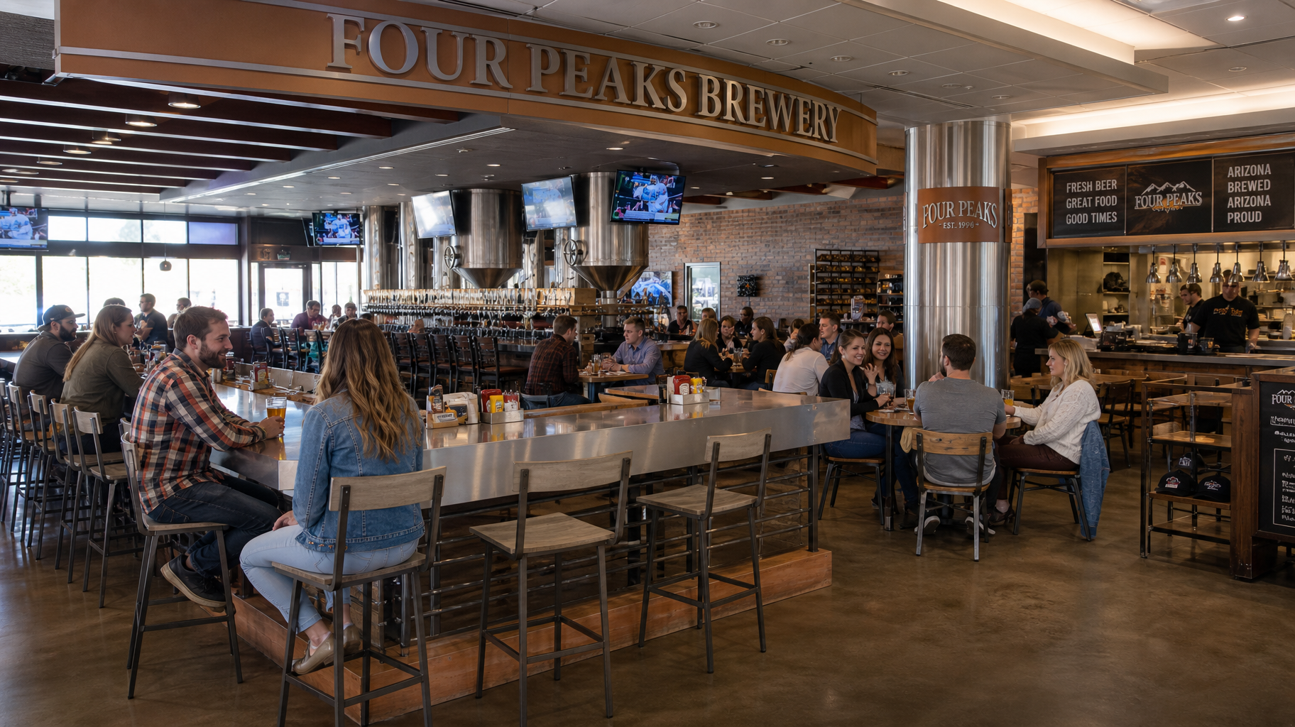 Busy brewery bar with patrons seated at tables under a Four Peaks Brewery sign