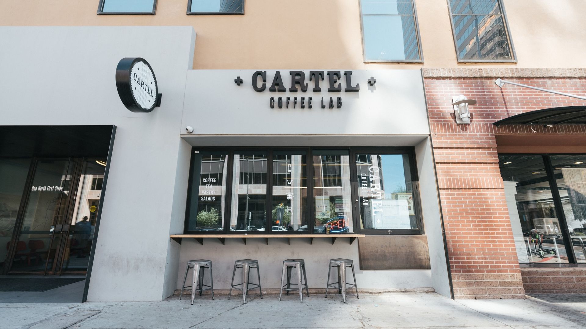 Cartel Coffee Lab storefront with a window, sign, and stools.