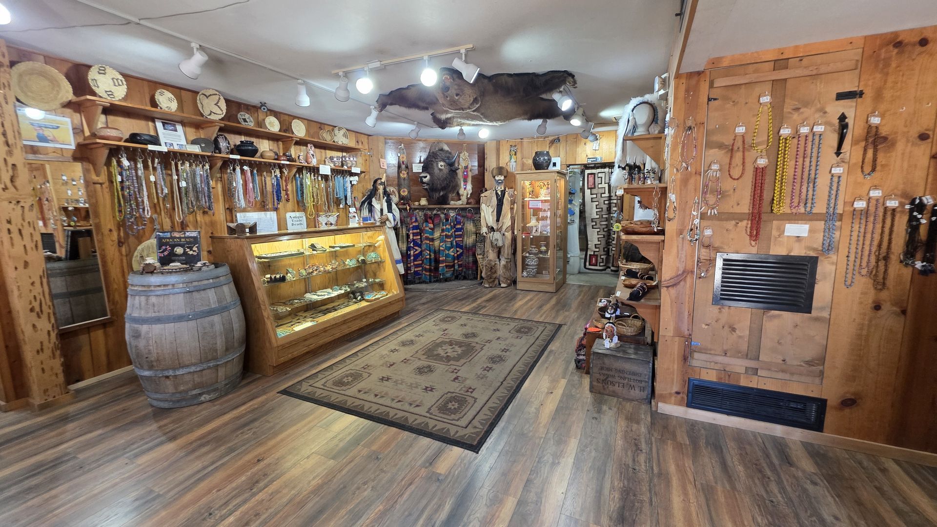 Inside a rustic shop, showcasing Native American crafts, jewelry, and leather goods on wooden walls and display cases.