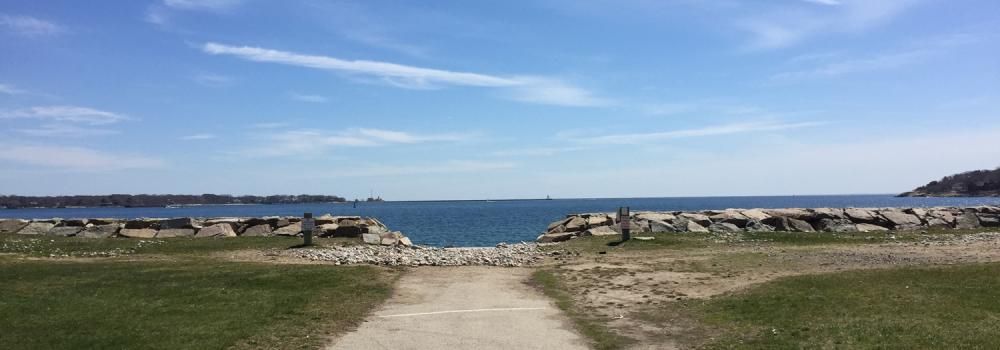A stone path leads to a serene blue ocean under a bright sky.