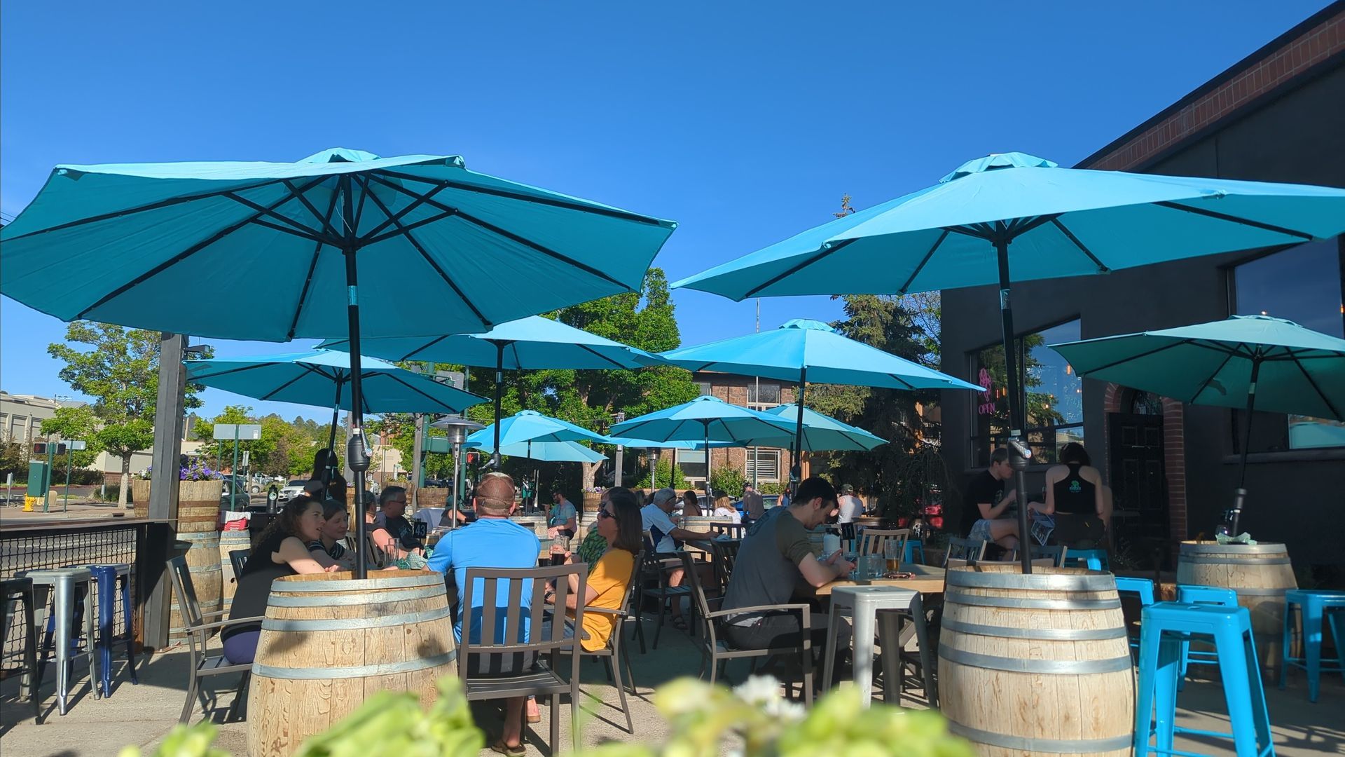 Outdoor restaurant seating with blue umbrellas, people at tables, sunny day.