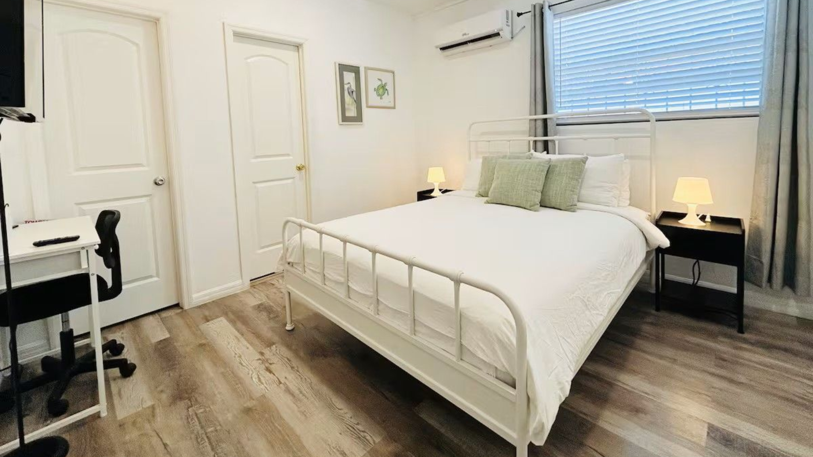 Bedroom with white bed, gray curtains, and desk.