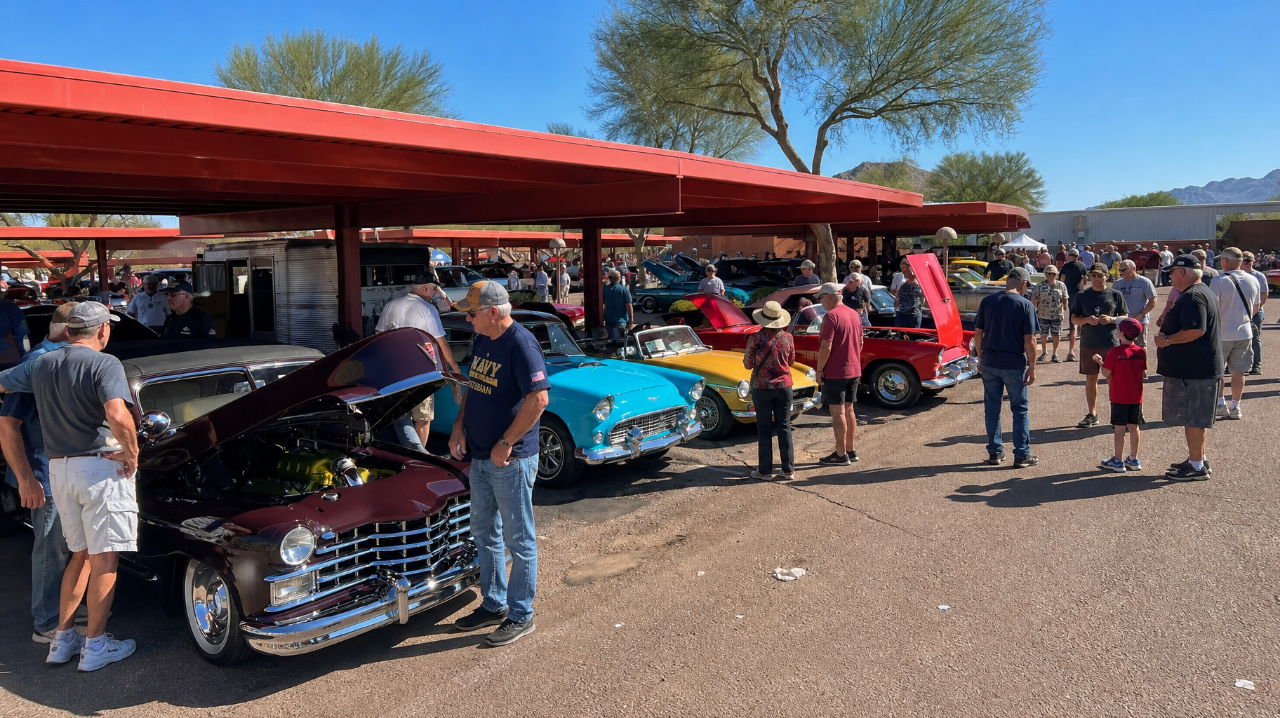 People browsing classic cars under a red canopy at an outdoor car show.