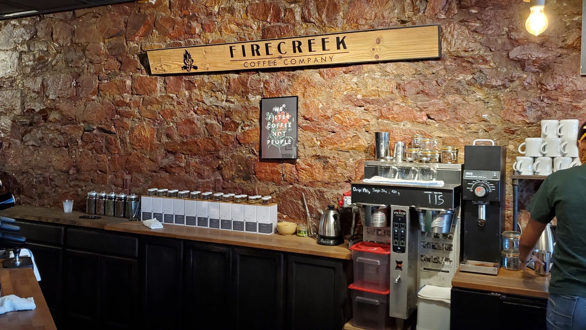 A rustic coffee shop interior featuring a natural stone wall, a wooden 