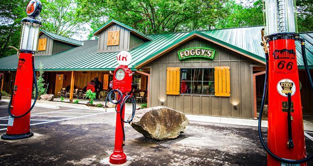 Foggy's restaurant with red gas pumps and a rock, set in a wooded area.