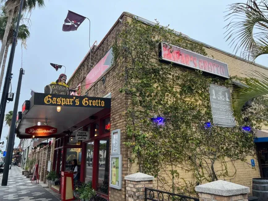 Pirate-themed restaurant, Gaspar's Grotto, with brick facade, climbing vines, pirate flags, and red accents.