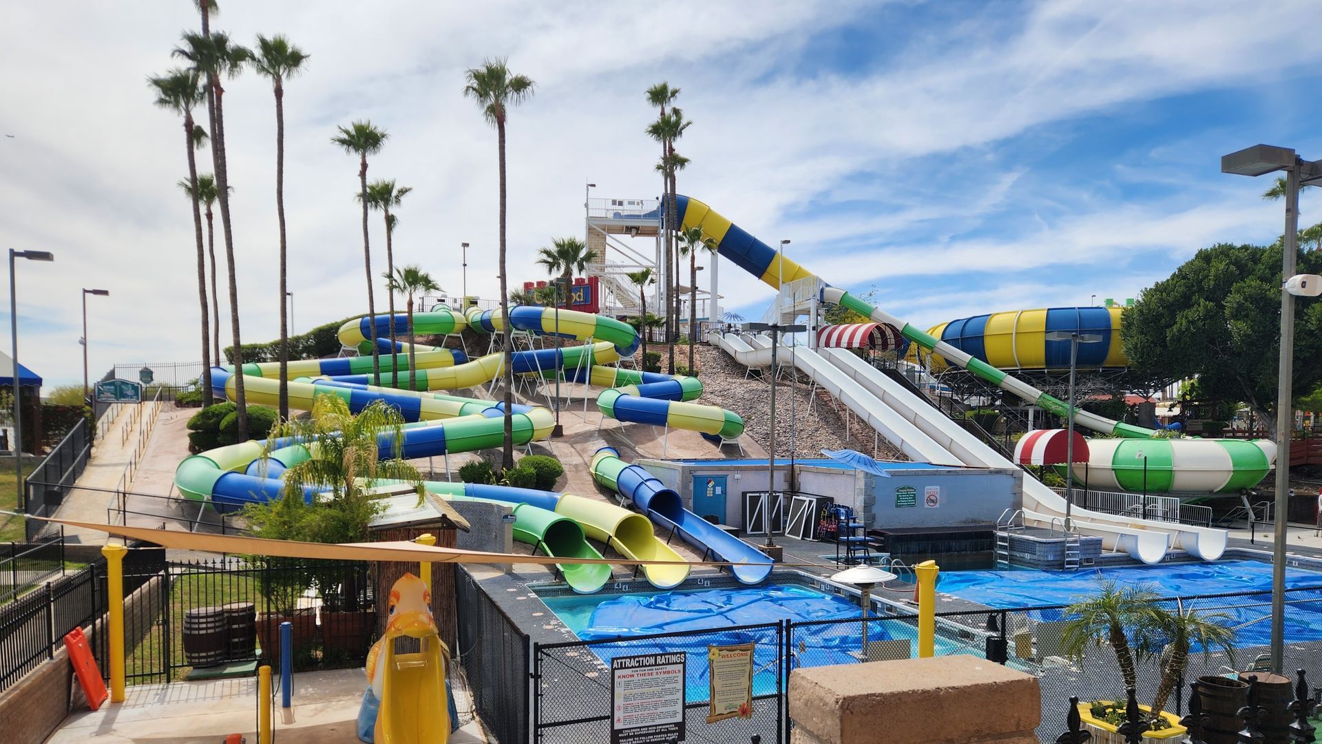 Water park with several colorful water slides and pools under a cloudy sky.