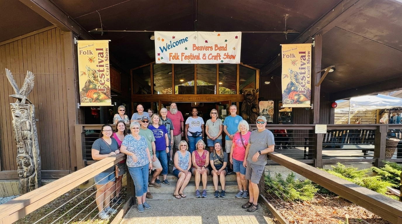 Group posed on a wooden stage under a colorful sign at an outdoor venue.