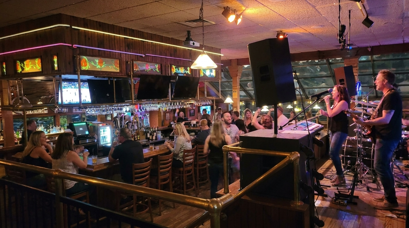 Live band playing in a dimly lit bar as patrons sit and watch at tables and the counter.
