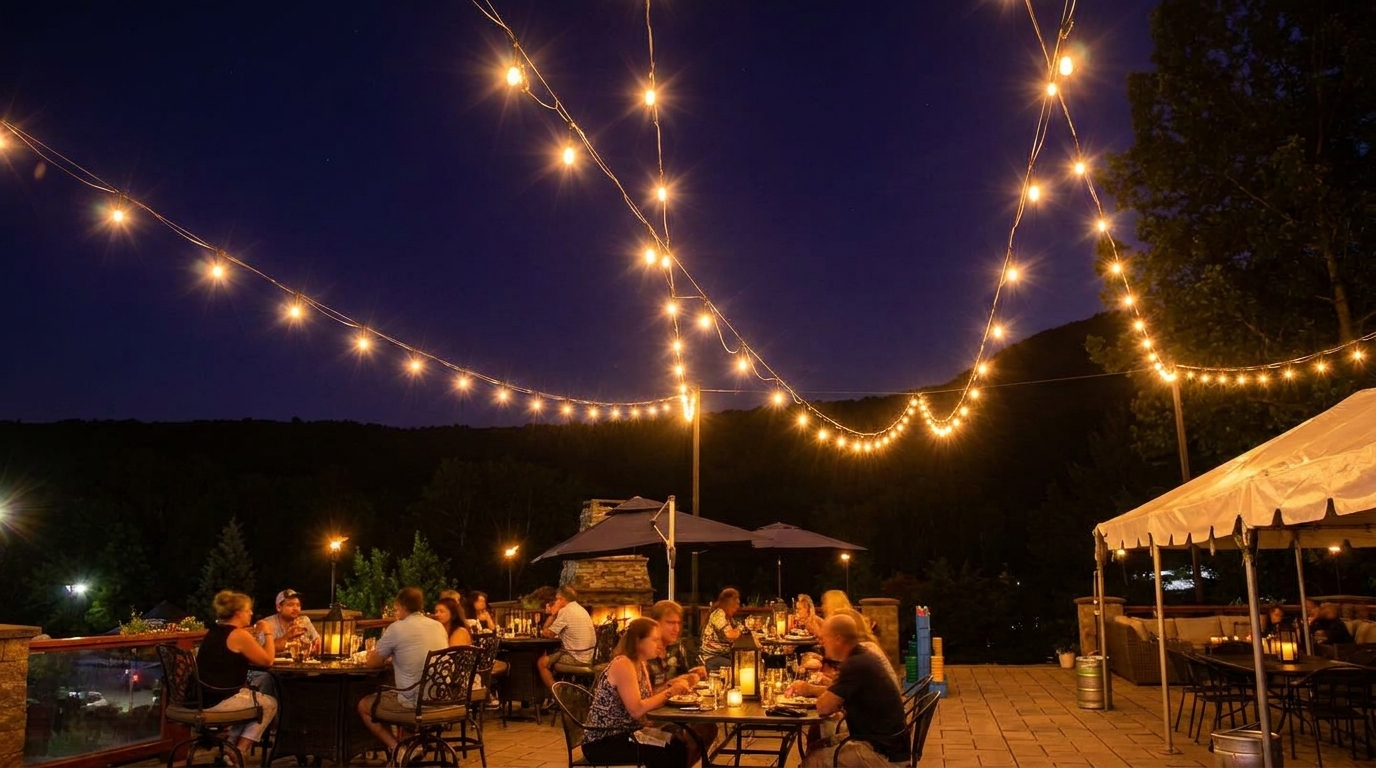 Outdoor evening dinner party under string lights, with guests seated at tables beneath a canopy tent.