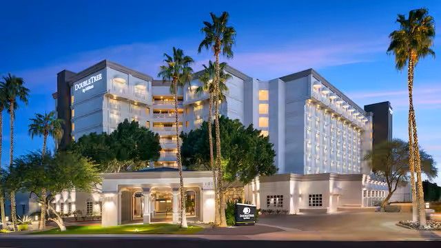 Hotel building with palm trees at dusk.