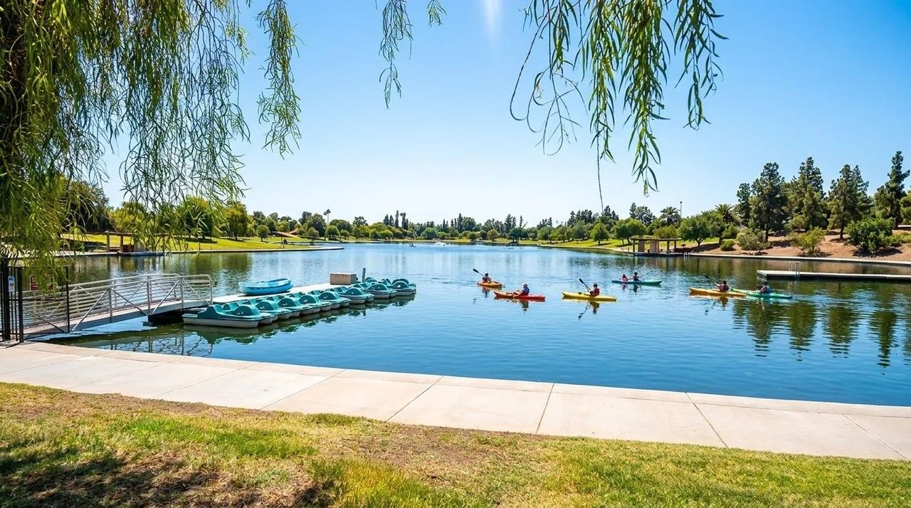 Lake with paddle boats on calm water, blue lounge chairs by the shore, and trees framing the scene.