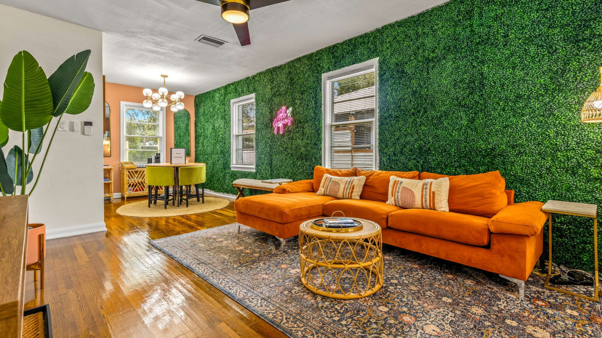 Living room with orange couch, green wall, and dining area.