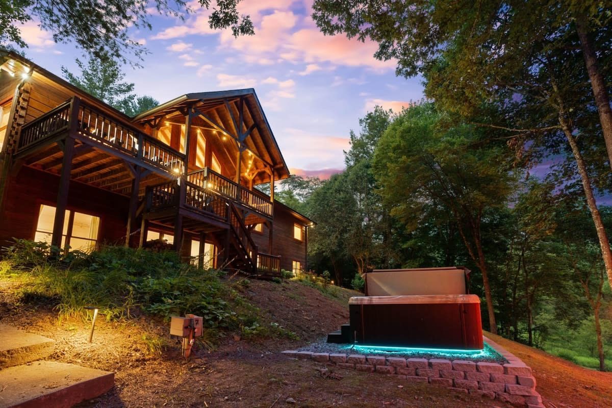 A large log cabin with a hot tub in front of it.