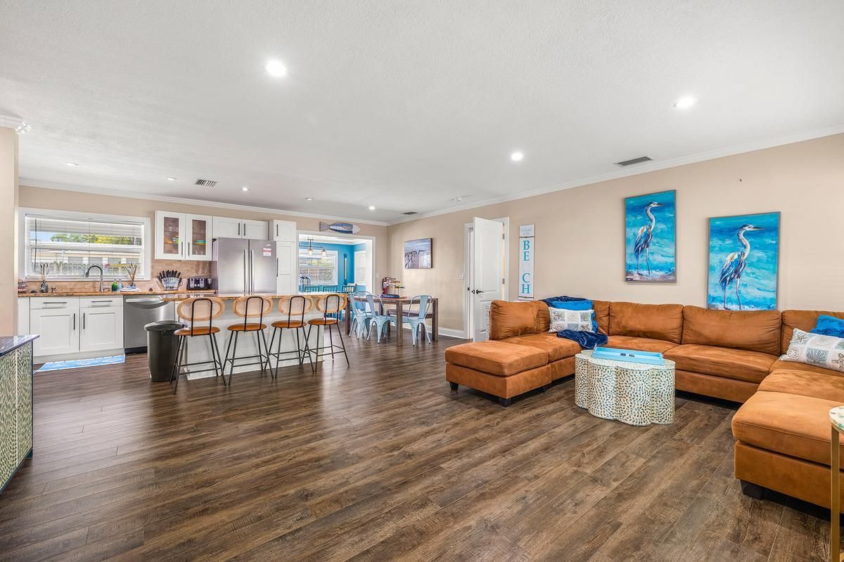 Modern open-concept living and kitchen area Spacious open-concept living room and kitchen with modern appliances, large sectional sofa, bar seating, and coastal decor