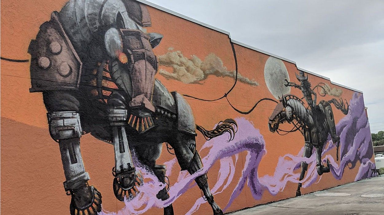 Mural of two armored, robotic-looking horses on an orange wall, with purple and white vapor trails.