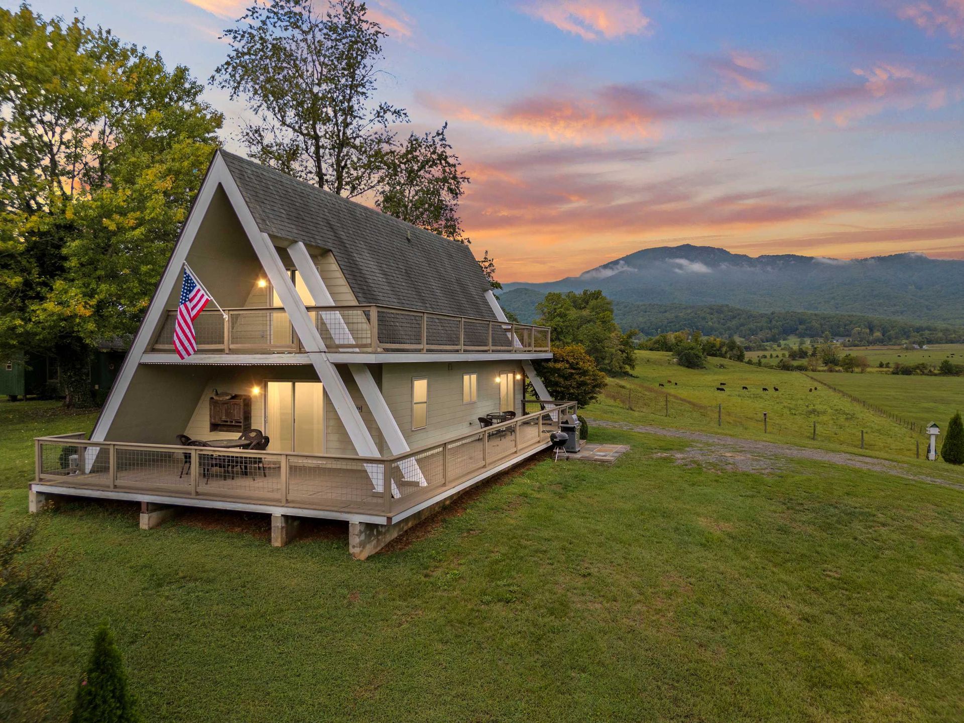 An a frame house with a large deck in the middle of a grassy field in Virginia.