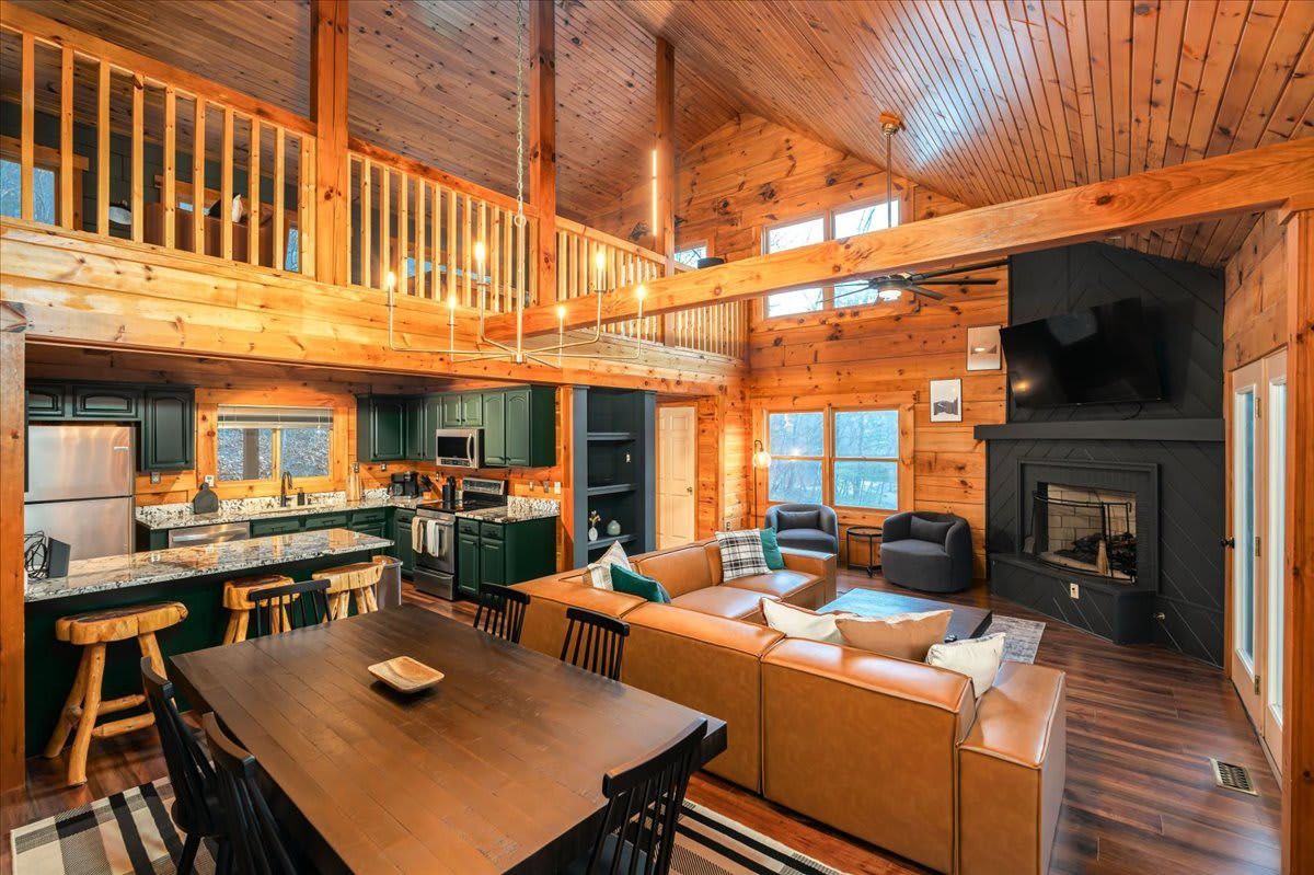 A large log cabin with a dining table , couch , chairs and a fireplace in Virginia. 