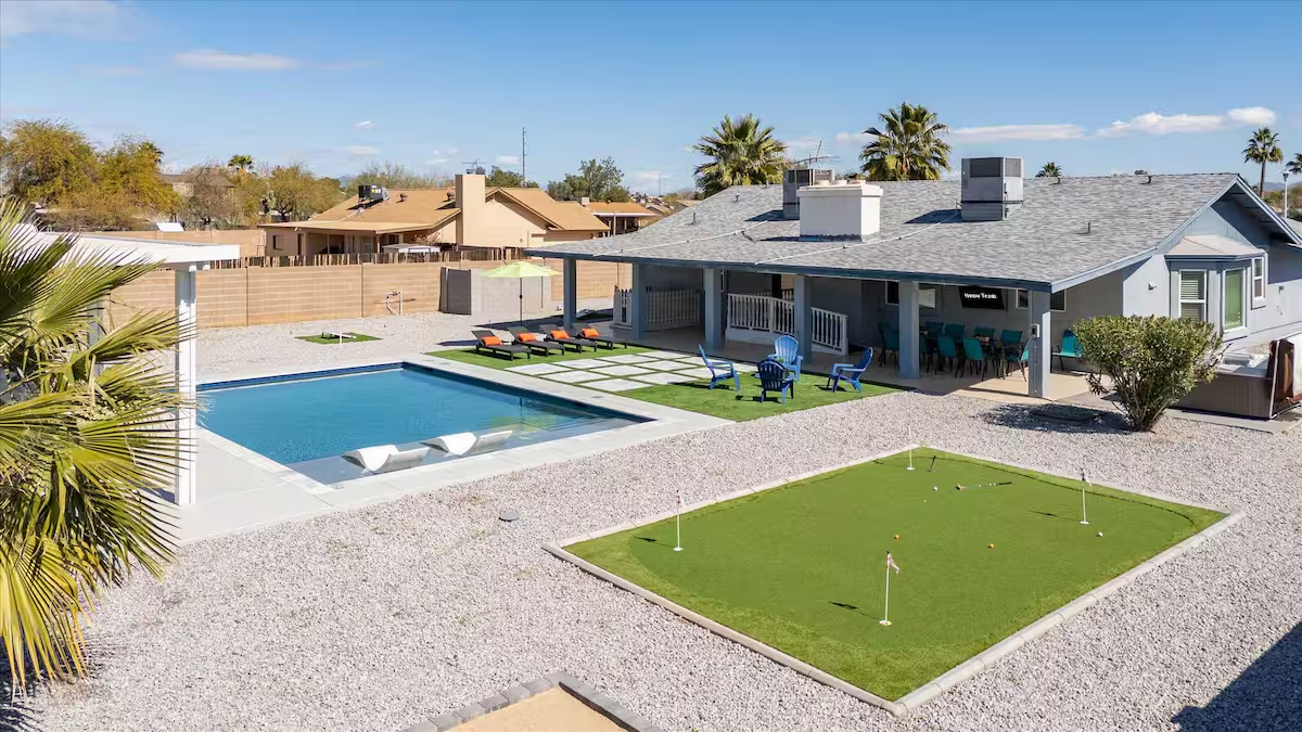 Modern house with backyard pool, putting green, and desert landscaping under a blue sky