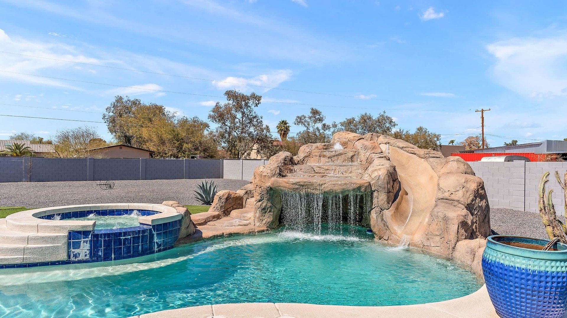 Private pool with waterfall and spa Resort-style backyard pool with rock waterfall feature, waterslide, and elevated spa — luxury vacation rental in Arizona