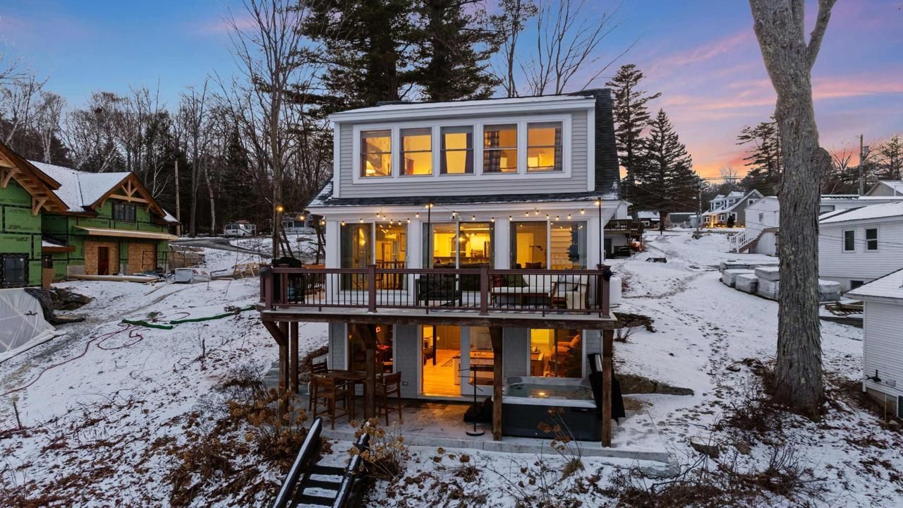 Winter Exterior New Hampshire STR New Hampshire vacation rental home exterior during winter with snow-covered grounds and sunset lighting.