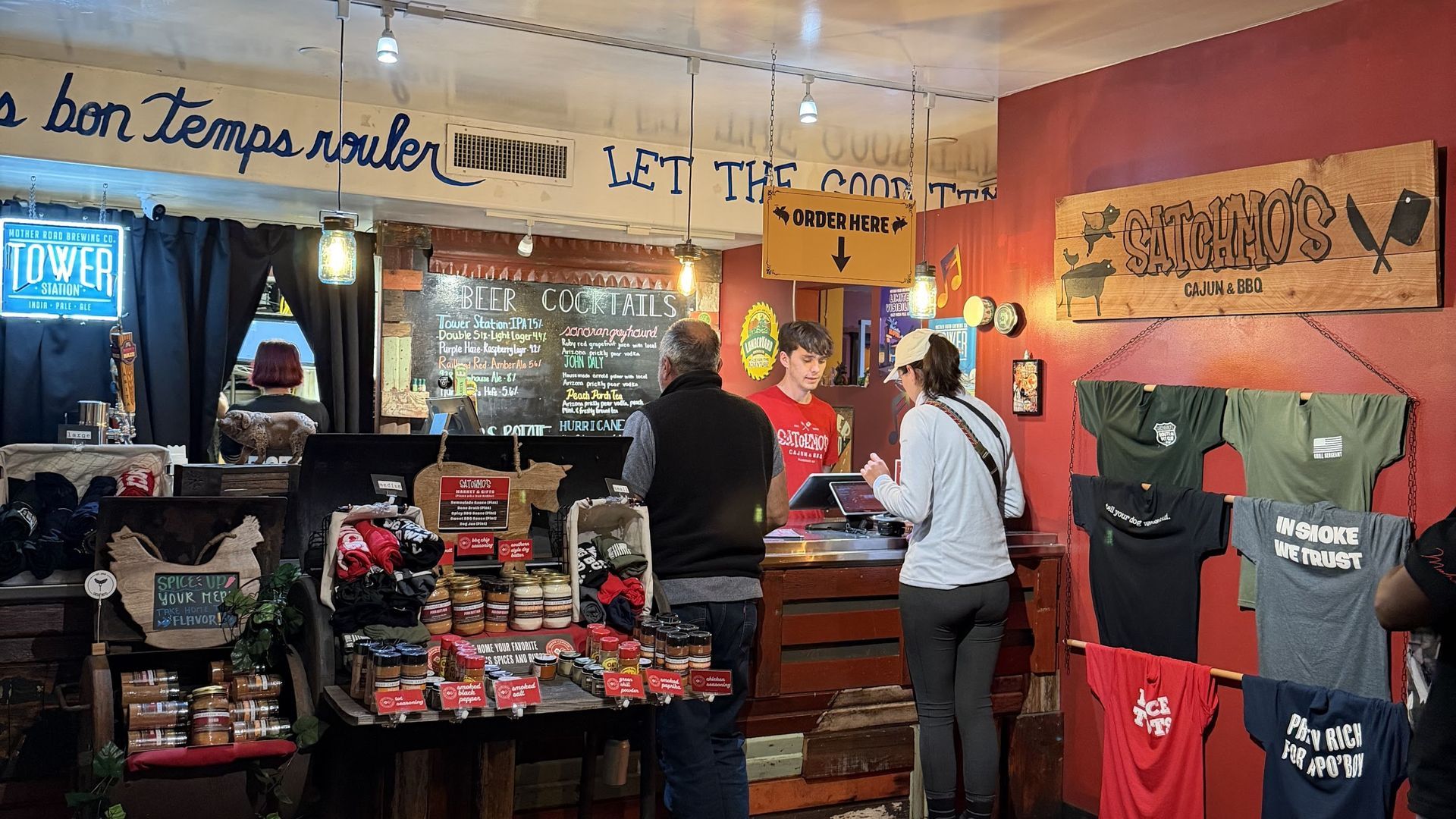 Inside a store: customers at a counter, products on display, signage with text above.
