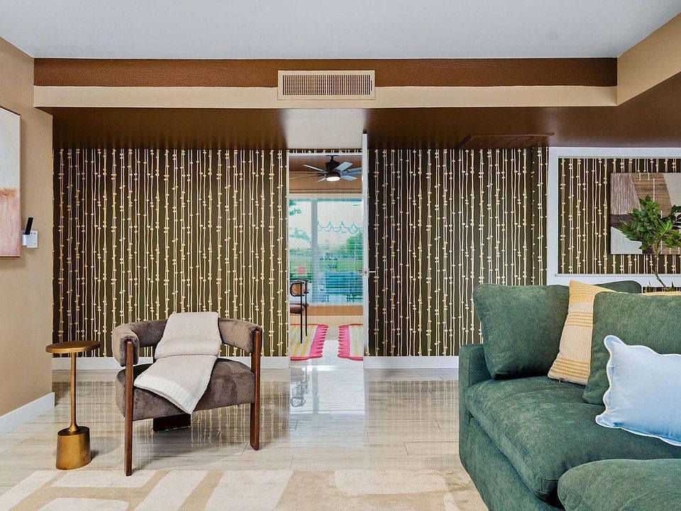 Modern living room with olive sectional, wood beams, large windows, and patterned accent wall