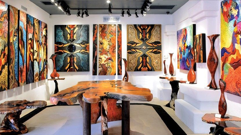 Art gallery with colorful abstract paintings and wooden sculptures.