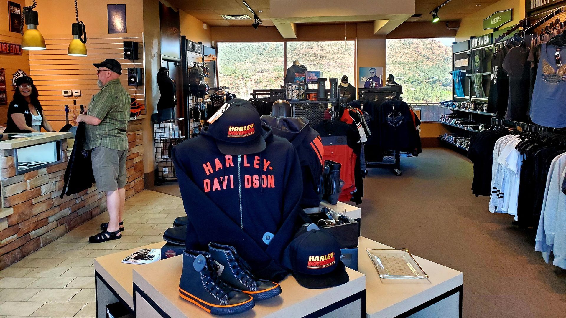 Harley-Davidson store interior with merchandise, a customer at the counter, and staff.