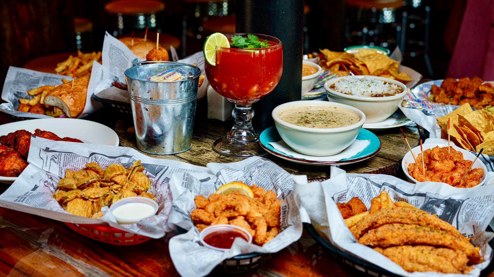 Table of various fried foods and drinks, including a Bloody Mary and fried seafood.